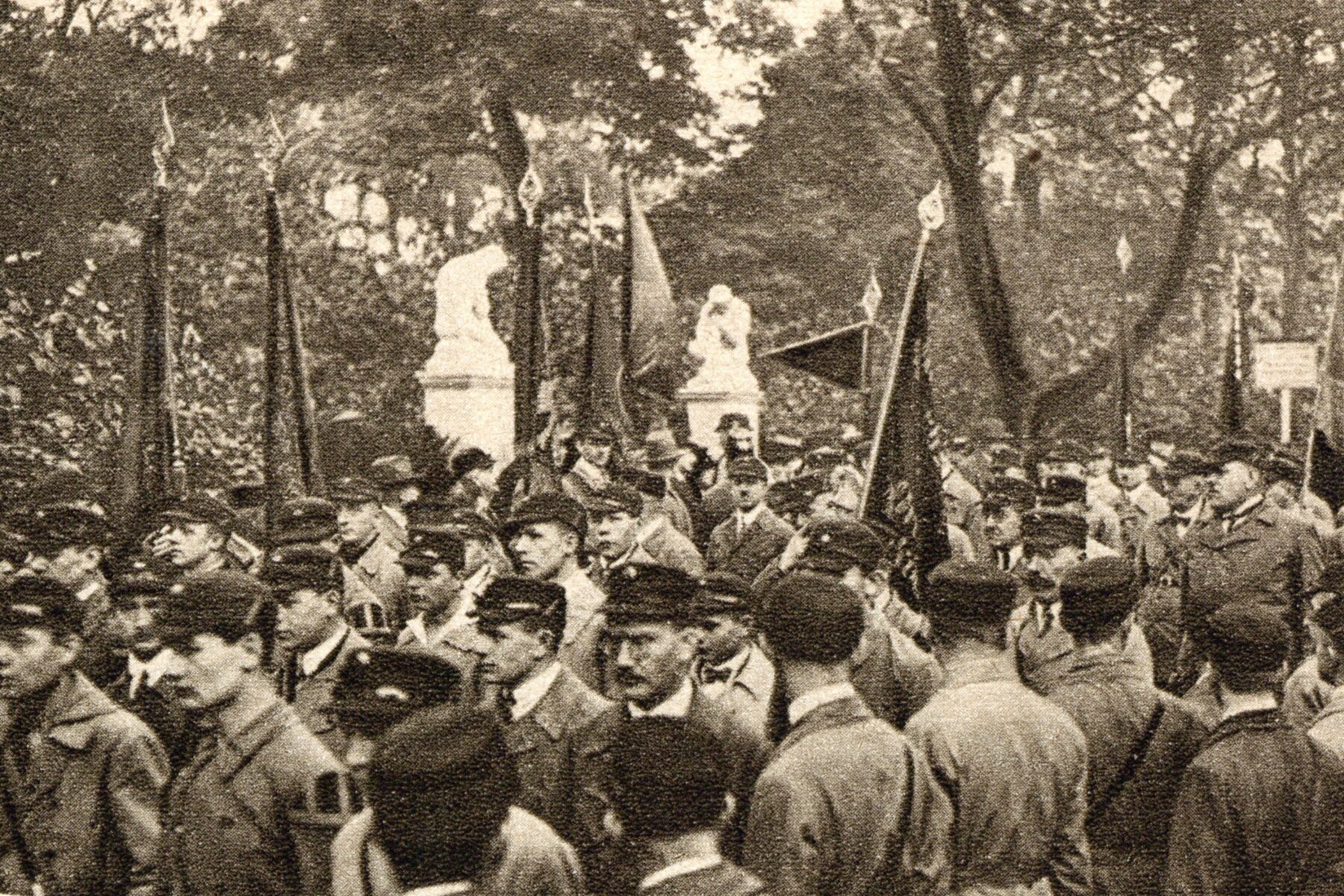 Historische Fotografie mit vielen Menschen in Uniformen, ein Portal ist im Hintergrund zu sehen.