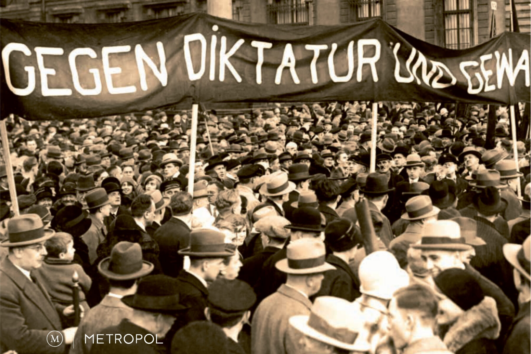 Historisches Bild einer Demonstration mit einer großen Menschenmenge. Es wird ein Banner hochgehalten, dort steht "Gegen Diktatur und Gewalt"